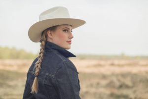 Retro cowgirl in jeans jacket in countryside